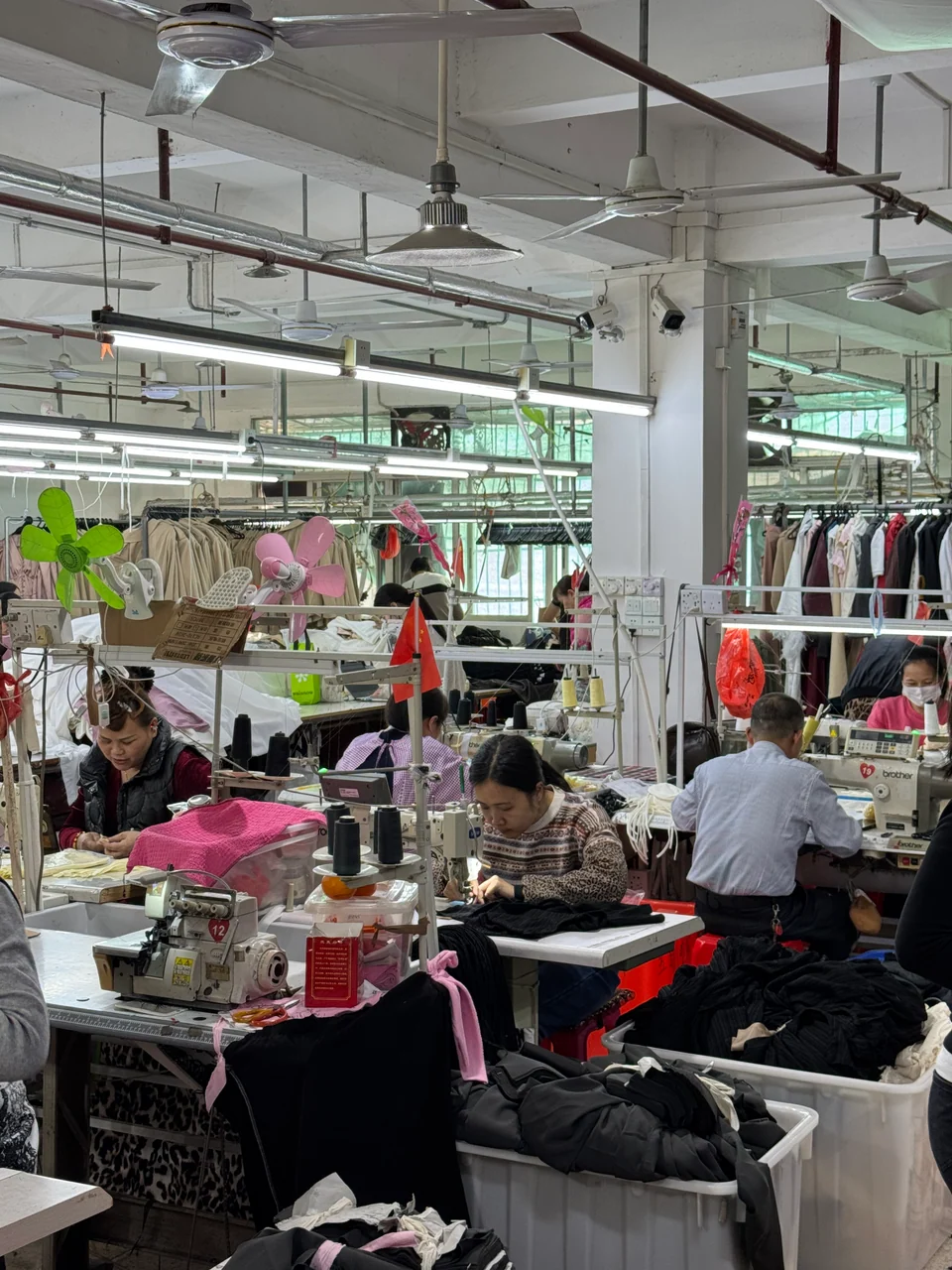 Garment workers using sewing machines at production workstations.