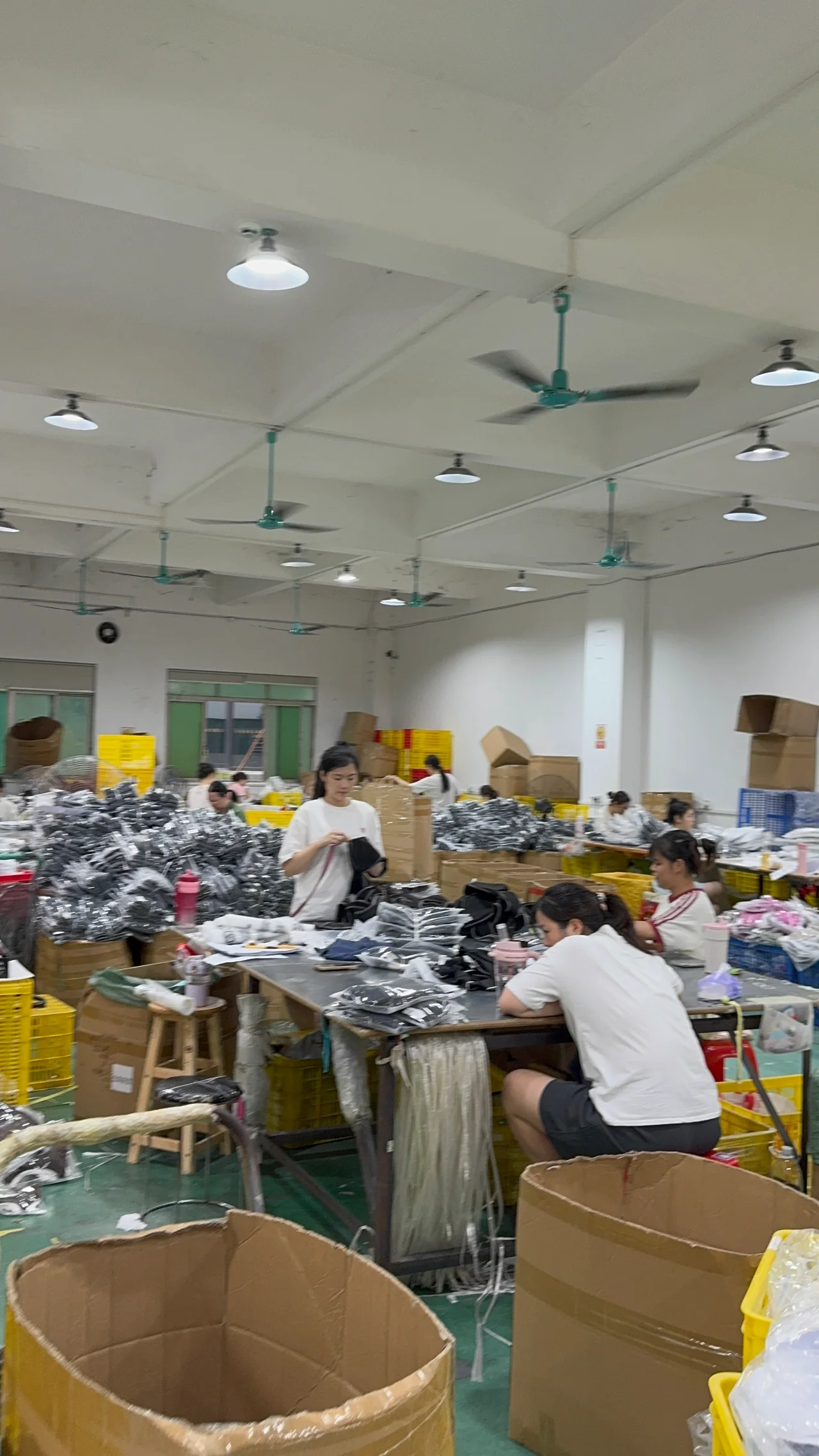 Workers handling garments and packaging in the packing area.