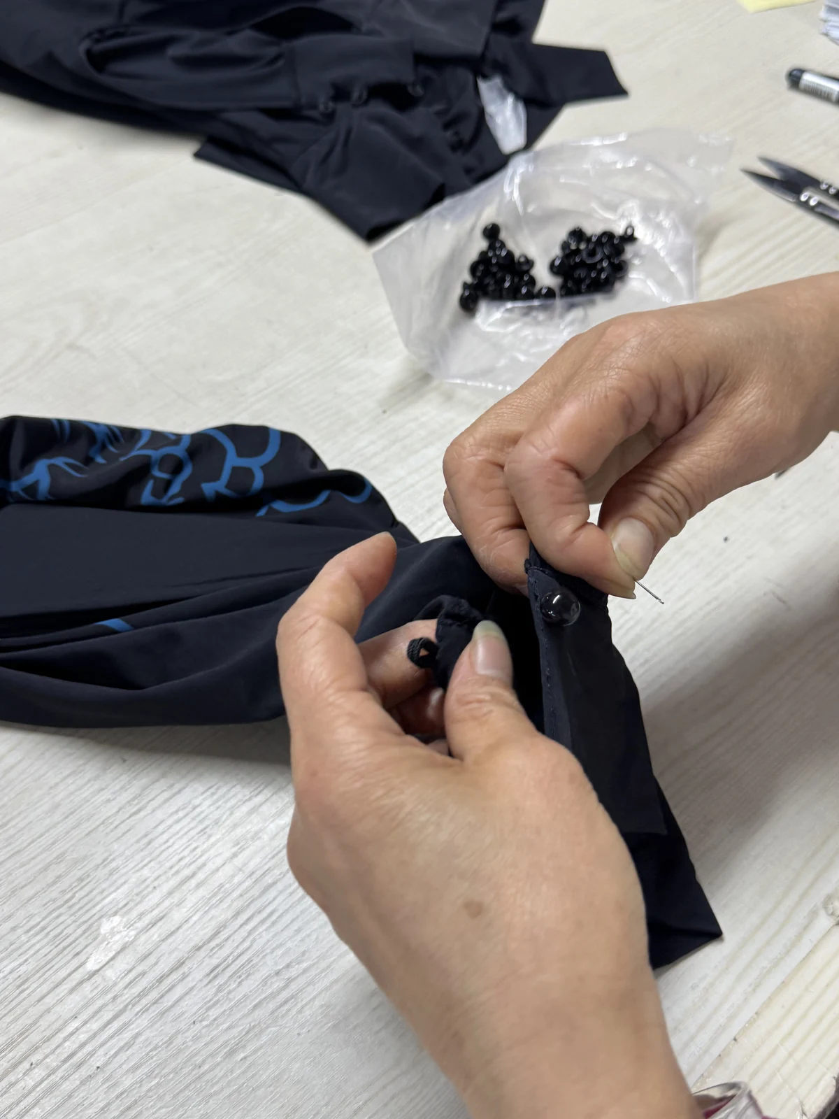 Hand-sewing a button onto a garment.