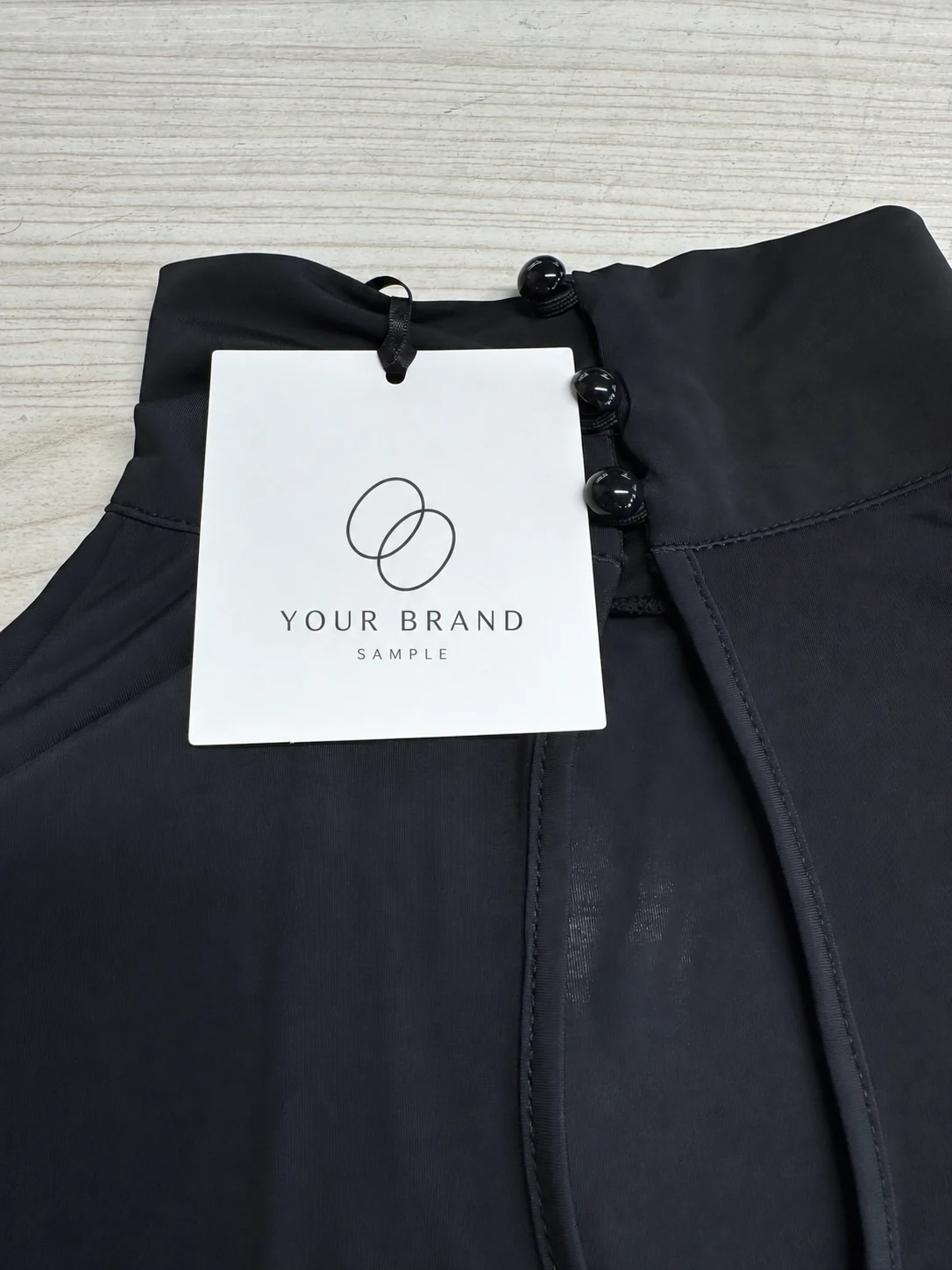 Garment hangtag with a digitally substituted generic YOUR BRAND SAMPLE logo.