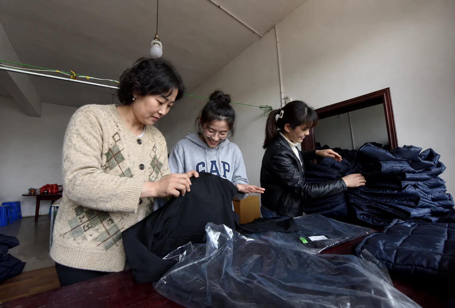 Inspecting dark-colored garments after bulk-order packing is complete.